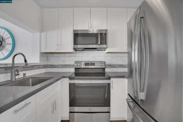 a kitchen with white cabinets and stainless steel appliances