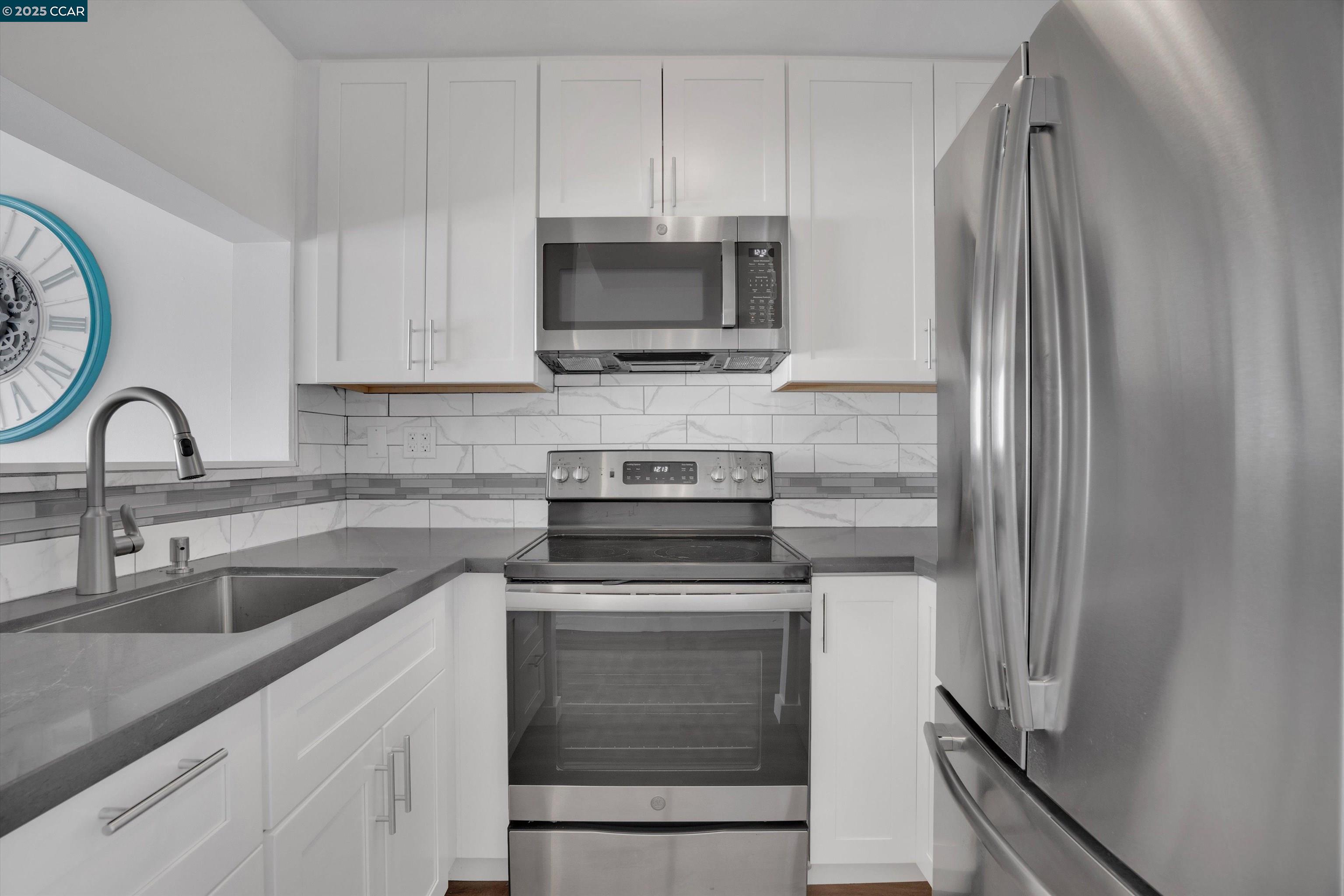 300 3rd Street, Unit 1203 San Francisco, CA 94107 - Photo 4 of 25 a kitchen with white cabinets and stainless steel appliances