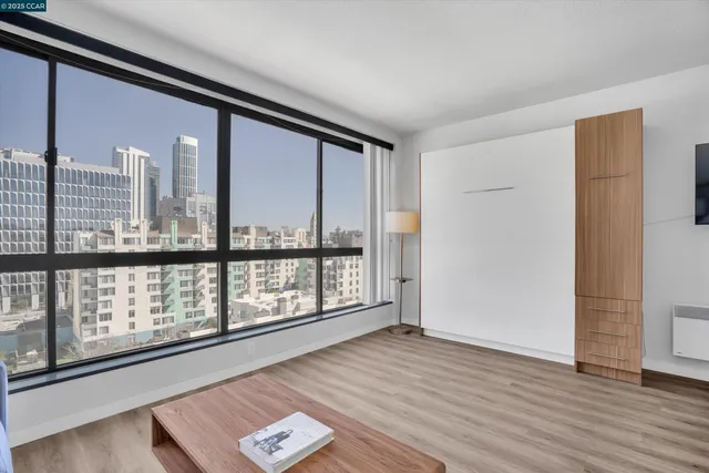 a view of an empty room with wooden floor and windows