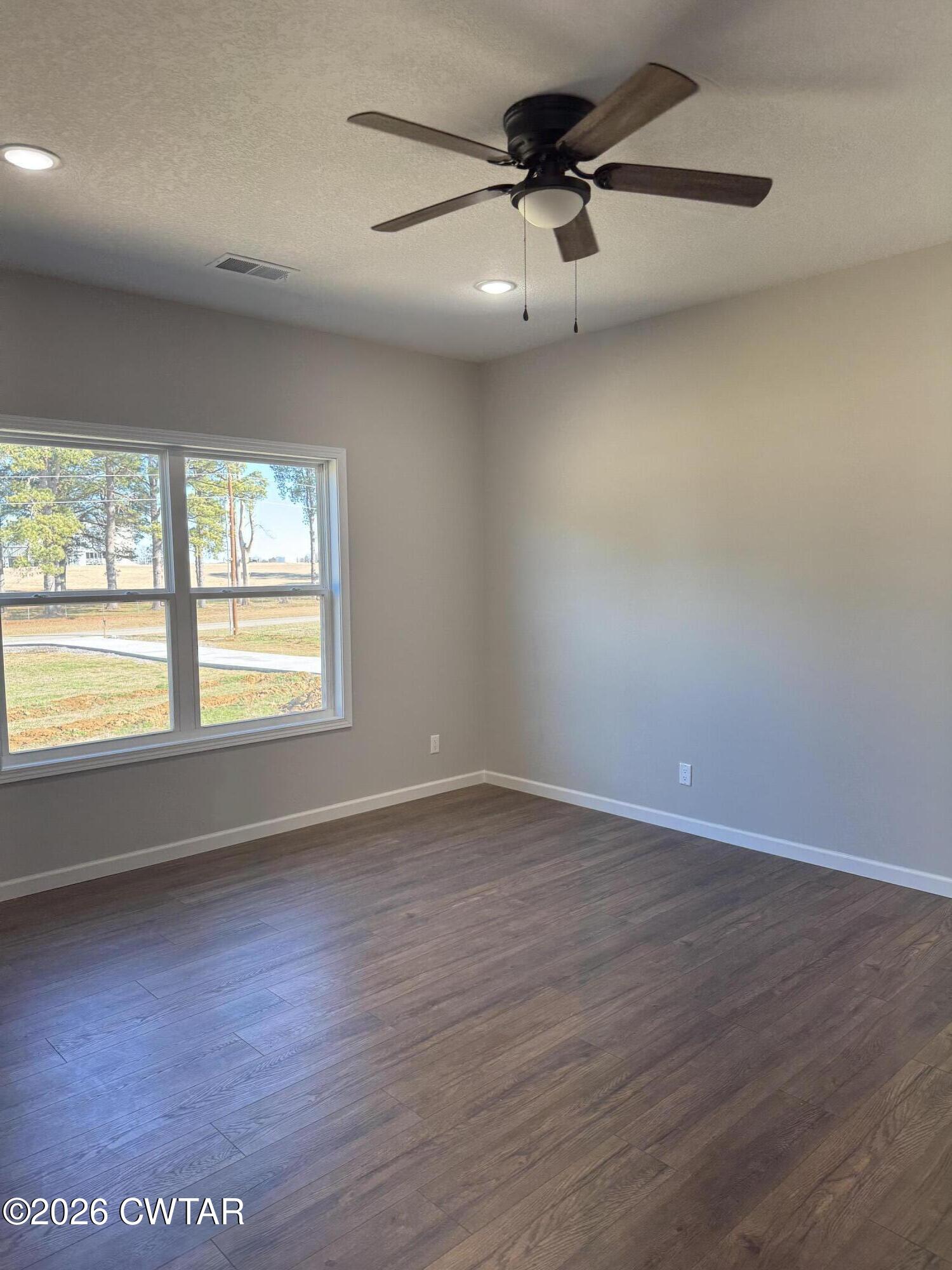 1380 Bonicord Road Dyersburg, TN 38024 - Photo 5 of 10 an empty room with wooden floor fan and windows
