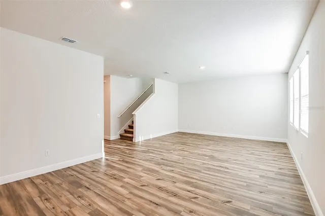 a view of empty room with wooden floor and stairs