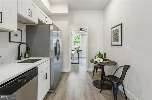 a kitchen with stainless steel appliances granite countertop a stove top oven a sink dishwasher and white cabinets with wooden floor