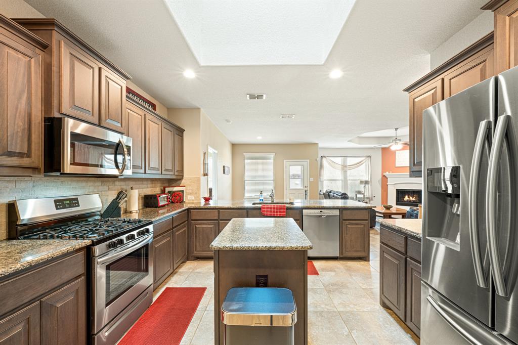 916 Falcon Road Argyle, TX 76226 - Photo 13 of 37 Kitchen featuring stainless steel appliances, a center island, tasteful backsplash, light stone counters, and kitchen peninsula