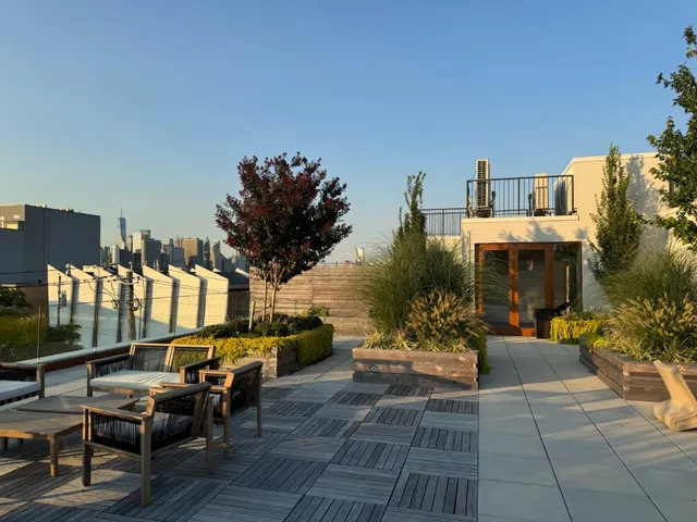 a roof deck with couches and potted plants with sky view