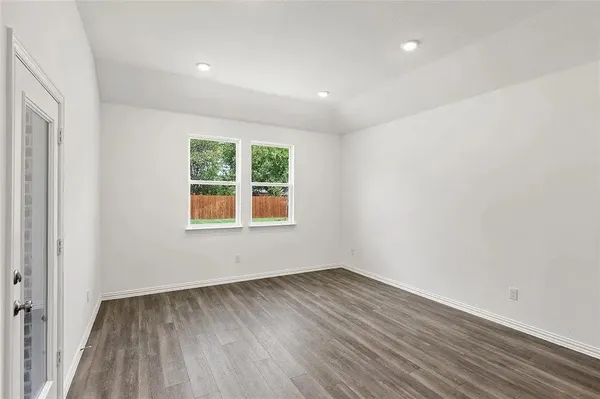 an empty room with wooden floor and windows