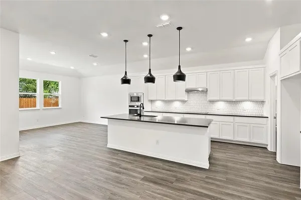 a kitchen with stainless steel appliances granite countertop a sink a refrigerator a stove a microwave and wooden floors