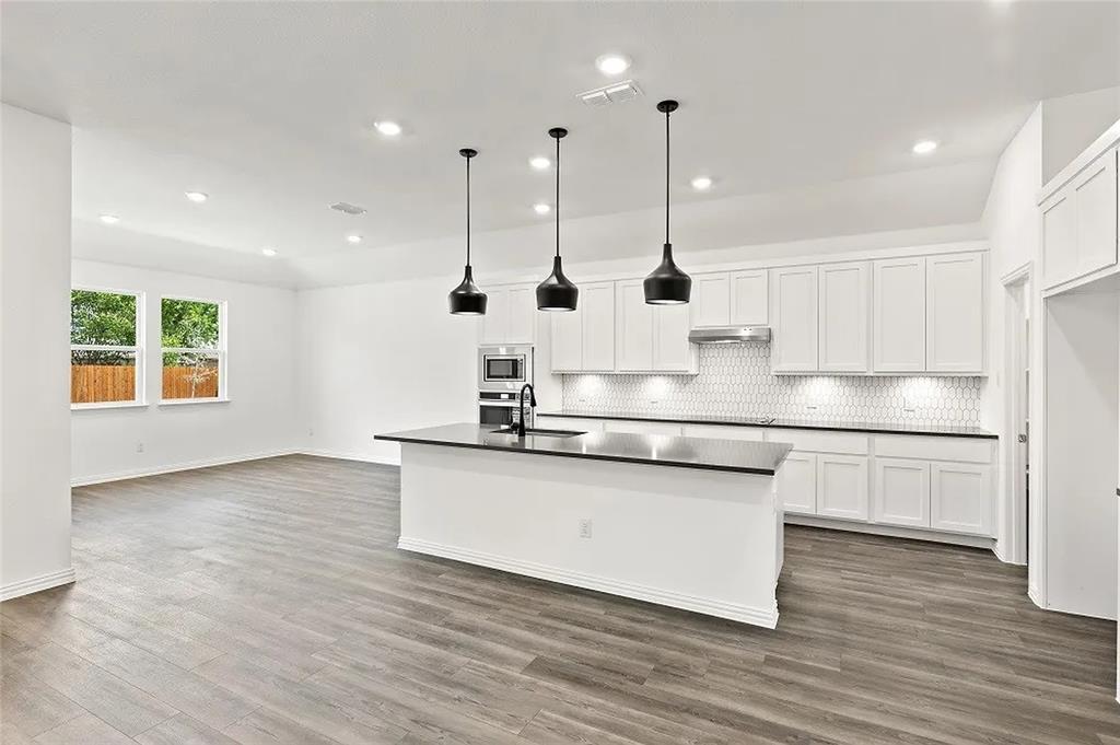 1632 Pavin Lane Fort Worth, TX 76052 - Photo 7 of 37 a kitchen with stainless steel appliances granite countertop a sink a refrigerator a stove a microwave and wooden floors