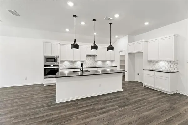 a kitchen with stainless steel appliances granite countertop a sink a stove and a wooden floors