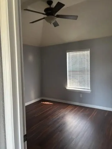 an empty room with wooden floor fan and windows
