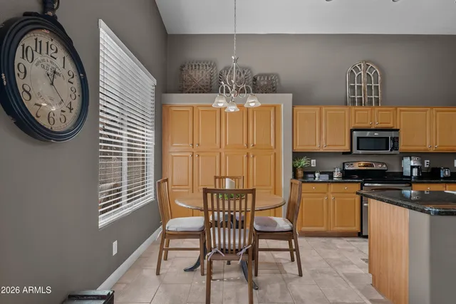 a kitchen with stainless steel appliances granite countertop a stove top oven a sink a dining table and chairs