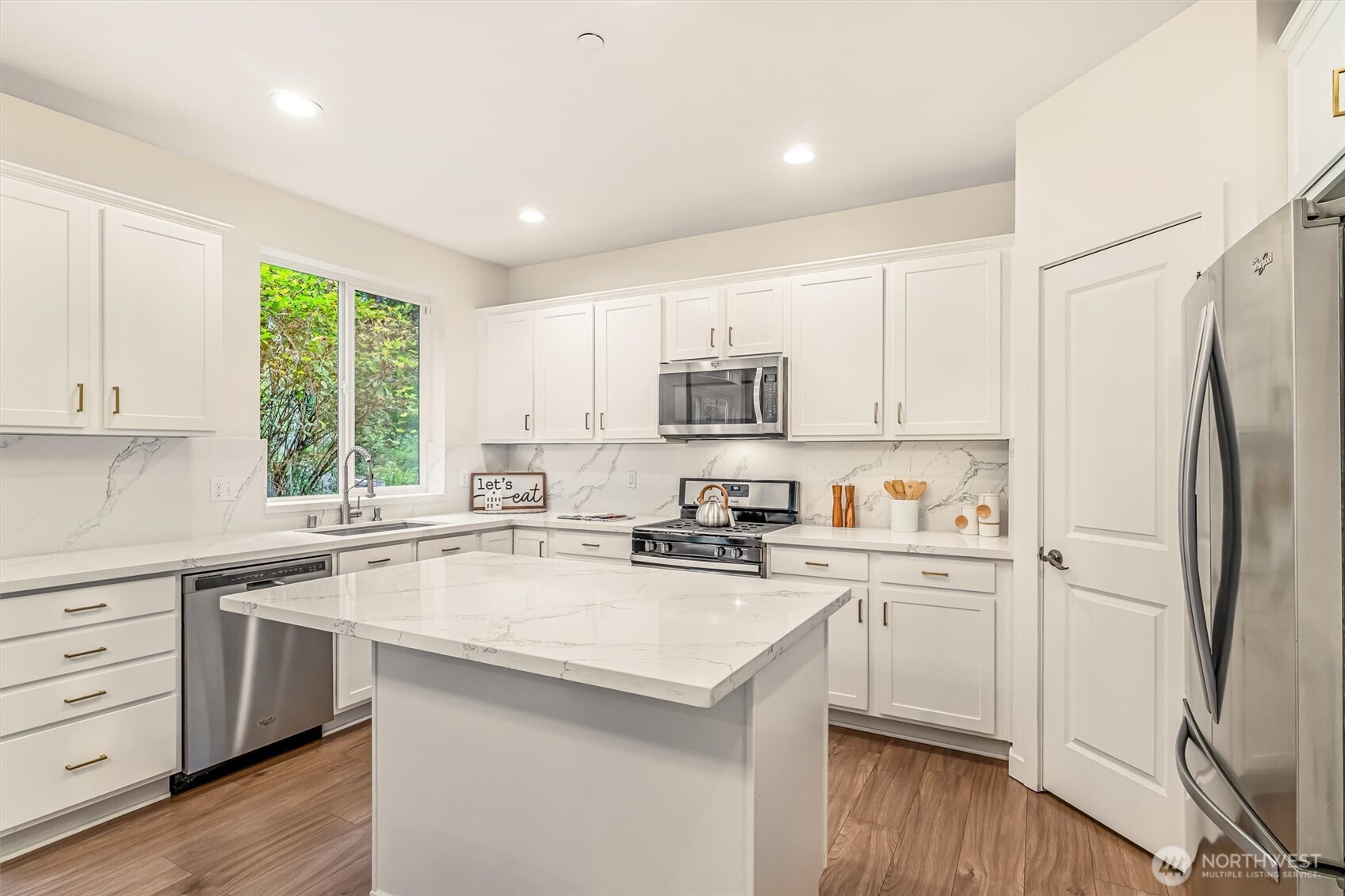 9213 Odin Way Bothell, WA 98011 - Photo 10 of 40 a kitchen with a refrigerator a sink dishwasher a stove and white cabinets with wooden floor