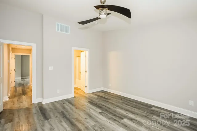a view of a room with wooden floor and a ceiling fan