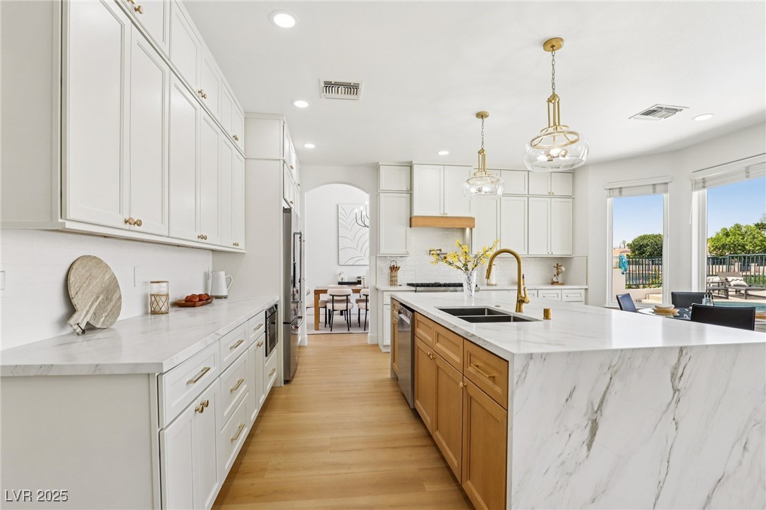 2469 Sun Reef Road Las Vegas, NV 89128 - Photo 33 of 93 Kitchen with arched walkways, recessed lighting, decorative backsplash, stainless steel appliances, and light wood-type flooring