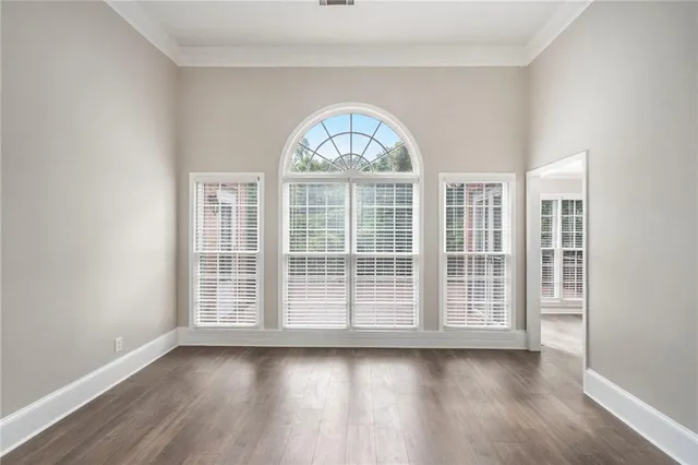 an empty room with wooden floor view and windows