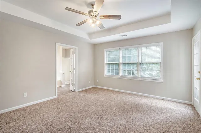 an empty room with chandelier fan and windows