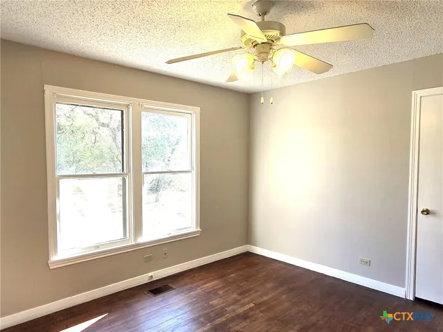 a view of an empty room with window and chandelier fan