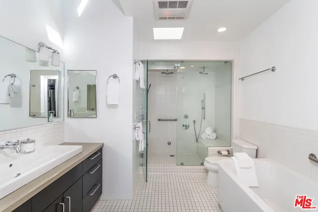 a bathroom with a tub sink shower and a mirror