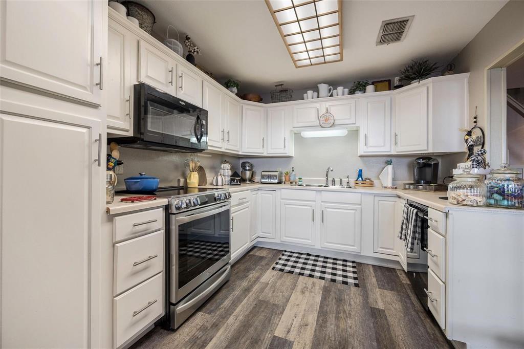 236 County Road 1422 Quitman, TX 75783 - Photo 20 of 34 Kitchen with black microwave, visible vents, stainless steel electric range, white cabinetry, and a sink
