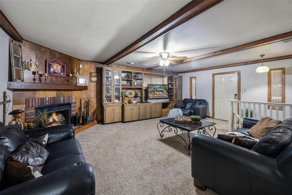 236 County Road 1422 Quitman, TX 75783 - Photo 7 of 34 Carpeted living room with wood walls, a textured ceiling, a fireplace, and beam ceiling