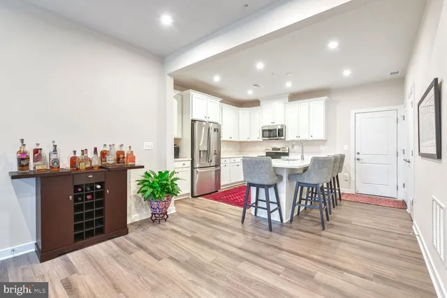 a kitchen with stainless steel appliances kitchen island granite countertop a refrigerator and a dining table