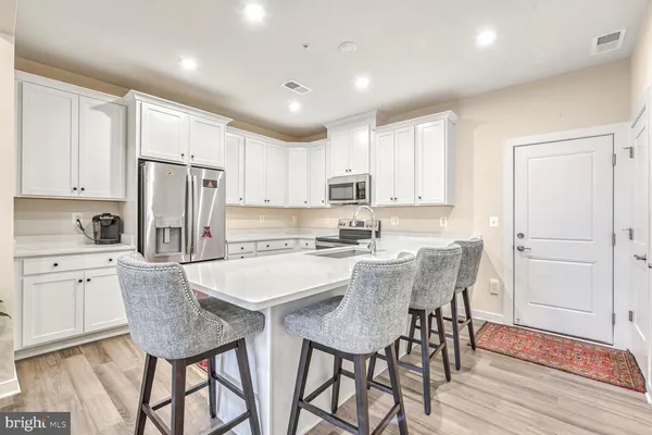 a kitchen with stainless steel appliances granite countertop a dining table chairs refrigerator and cabinets