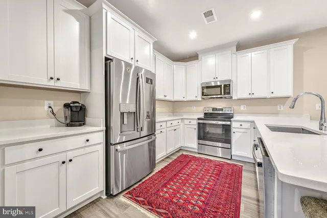 a kitchen with white cabinets and stainless steel appliances