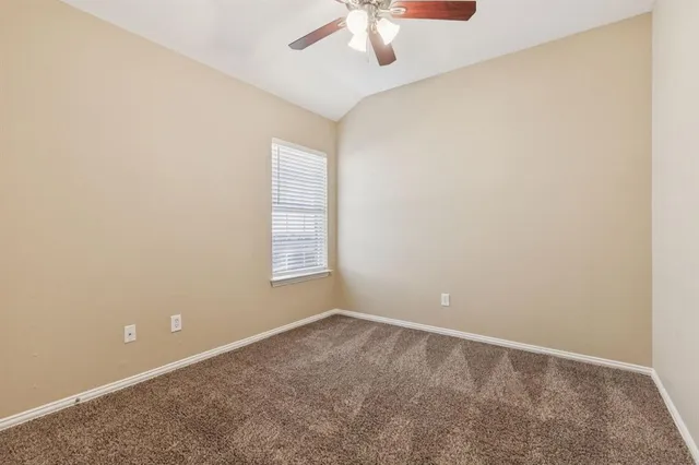 an empty room with a chandelier fan and windows