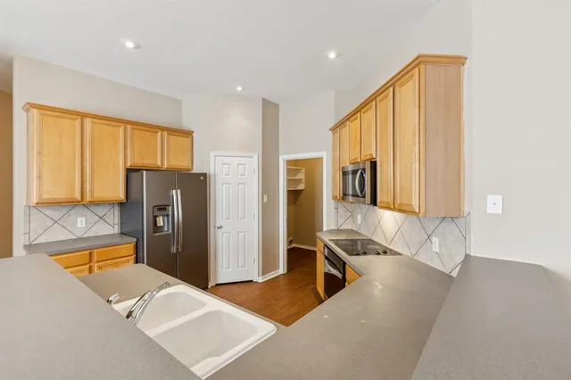a living room with stainless steel appliances furniture windows and a kitchen view