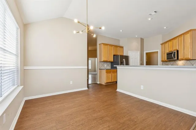 a view of kitchen with kitchen island a refrigerator wooden floor and a window