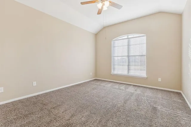 an empty room with windows and chandelier fan