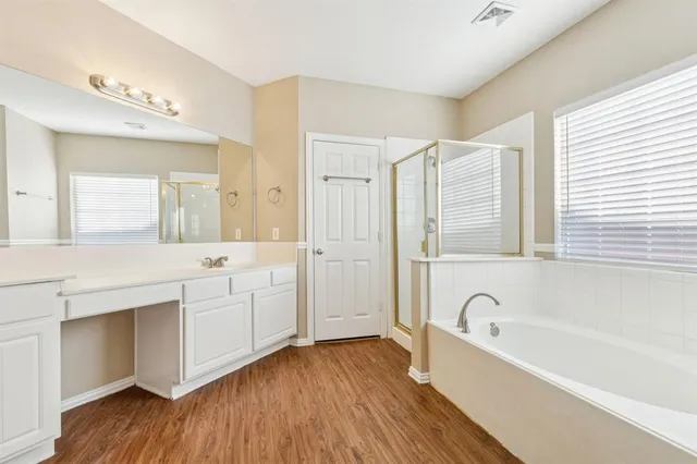 a bathroom with a granite countertop tub sink shower and mirror
