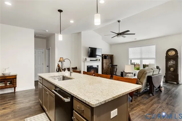 a kitchen with a stove a sink dishwasher a dining table and chairs with wooden floor