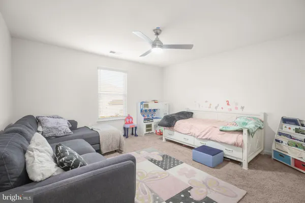 a bed room with a bed couch and a ceiling fan