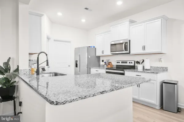 a kitchen with granite countertop a sink a stove and refrigerator