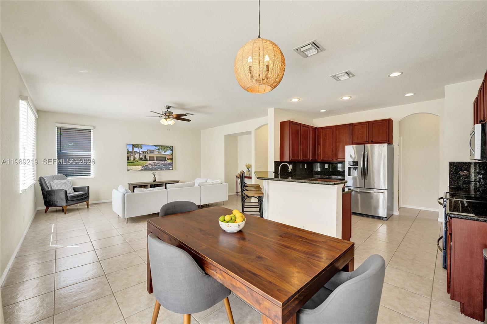 3936 Cascade Terrace Weston, FL 33332 - Photo 14 of 90 a kitchen with stainless steel appliances granite countertop a stove refrigerator a sink dishwasher a dining table and chairs with wooden floor