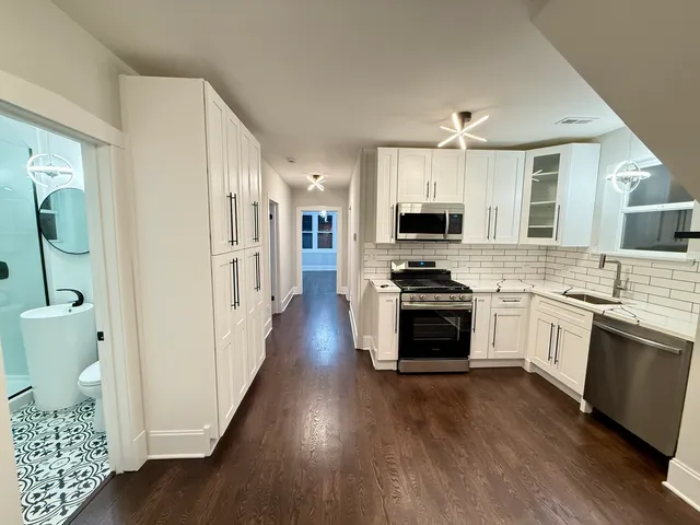 a kitchen with granite countertop a stove top oven a sink dishwasher a dining table and a stove with wooden floor