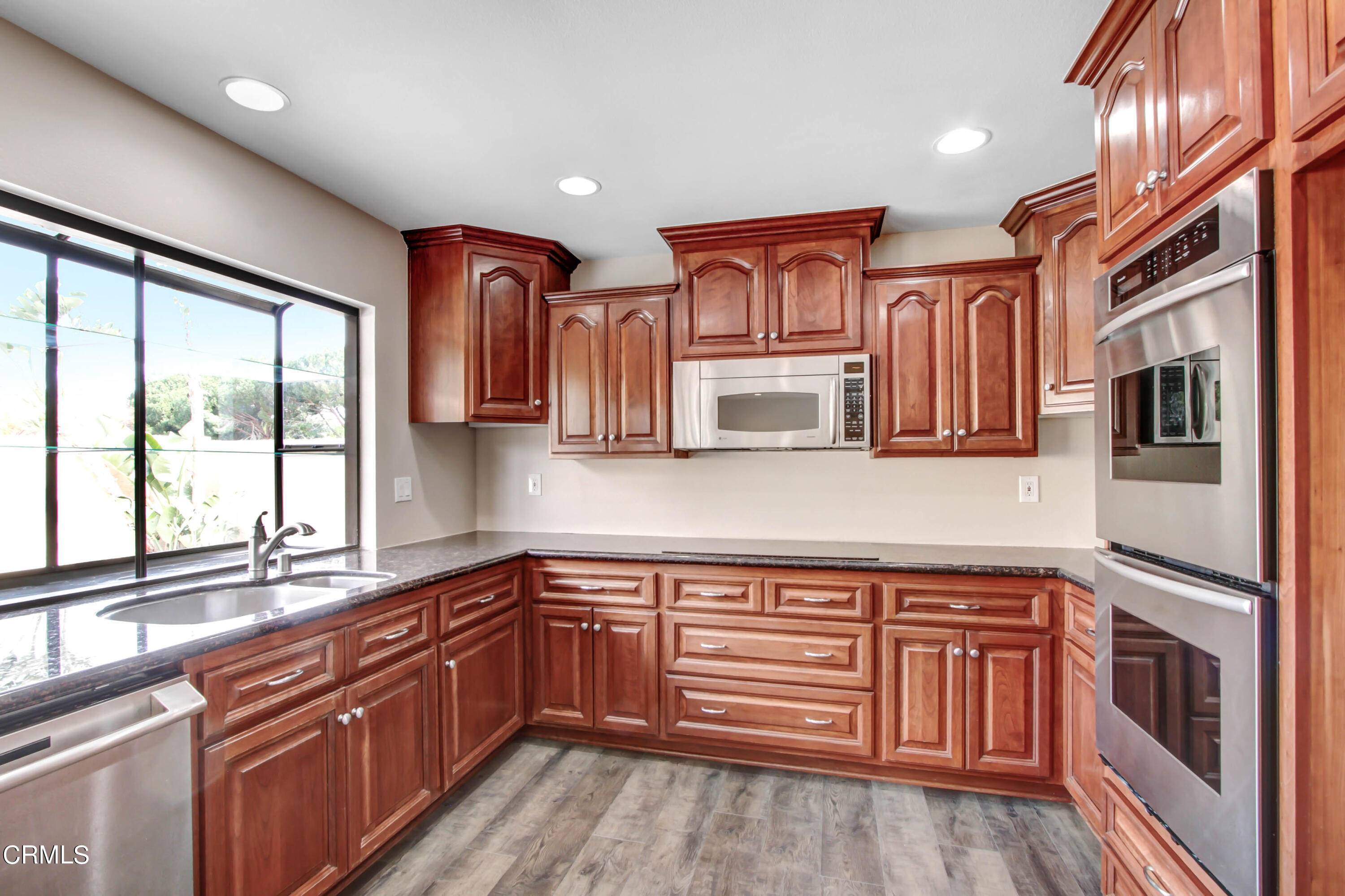 a kitchen with stainless steel appliances granite countertop a refrigerator and wooden cabinets