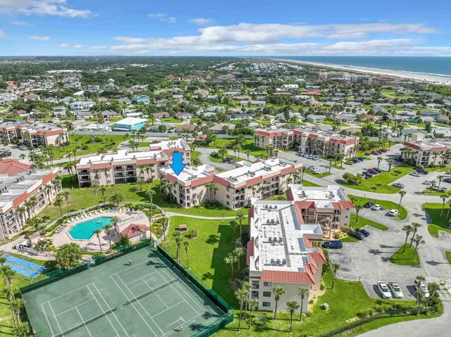 an aerial view of a house with swimming pool and trees in the background