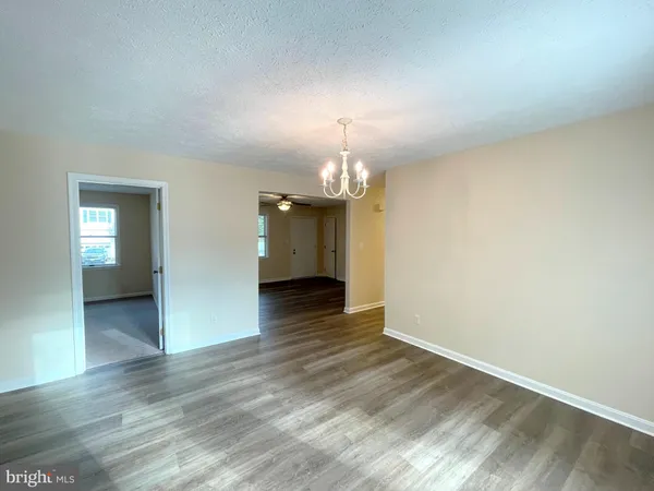 a view of a livingroom with wooden floor and a kitchen
