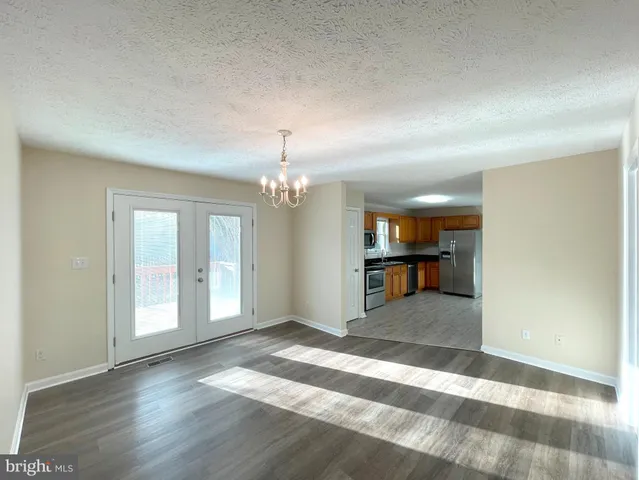 an empty room with wooden floor chandelier and windows