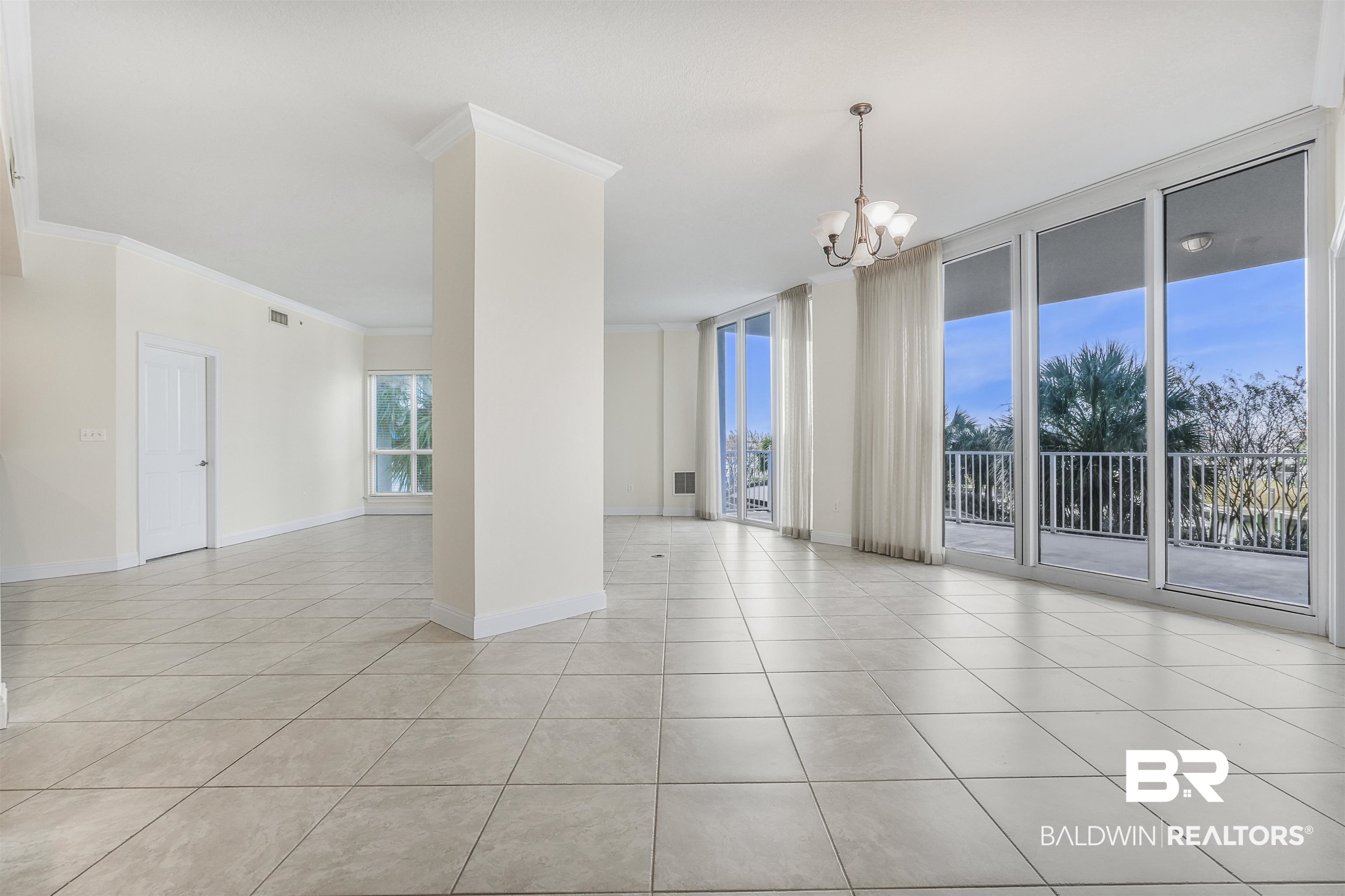 28250 Canal Road, Unit 106 Orange Beach, AL 36561 - Photo 8 of 50 Spare room with a wall of windows, a chandelier, crown molding, and light tile patterned floors