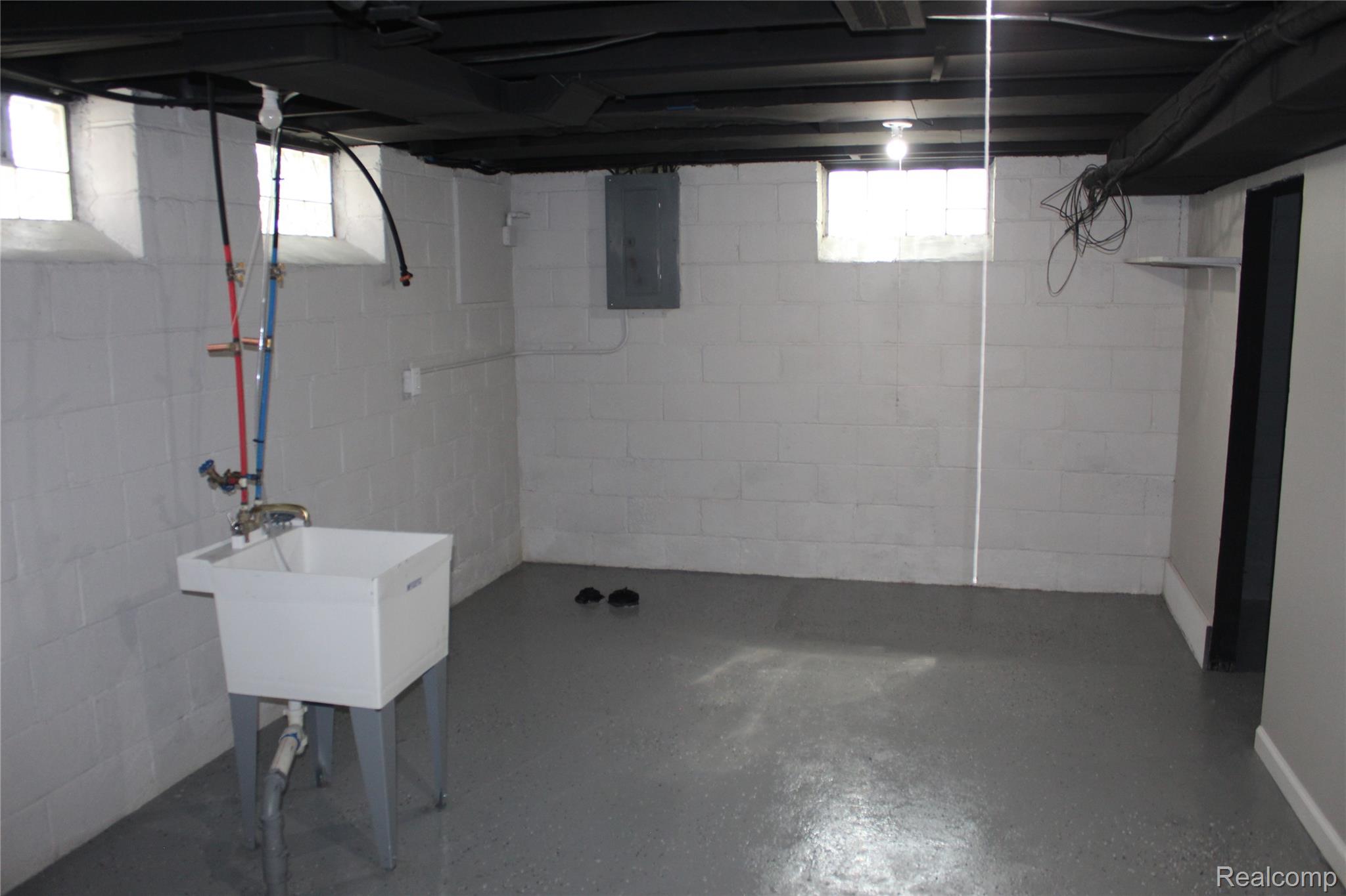 5543 Balfour Road Detroit, MI 48224 - Photo 29 of 54 Finished basement space featuring a utility sink, light gray concrete flooring, painted cinder block walls, exposed ceiling joists, and a partial drywall section