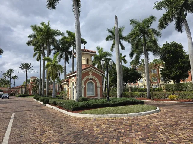 a front view of multi story residential apartment building with yard and green space