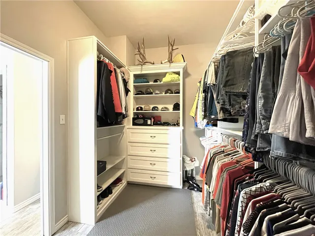 a view of walk in closet with clothes and shoes