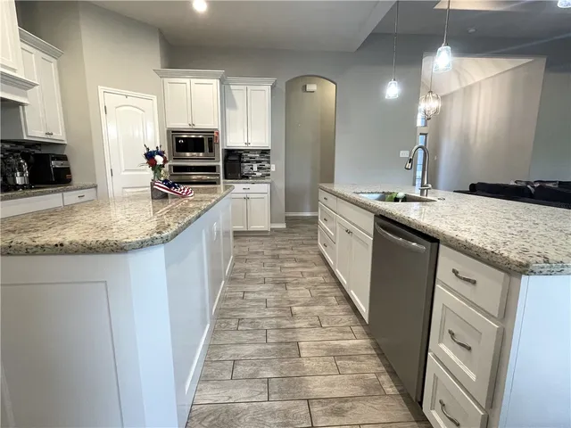 a large kitchen with granite countertop a sink and dishwasher a stove with wooden floor