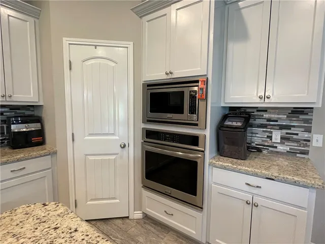 a kitchen with granite countertop white cabinets and stainless steel appliances