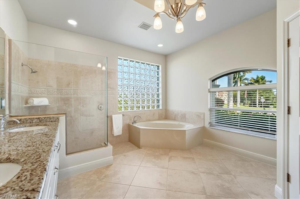560 Inlet Drive Marco Island, FL 34145 - Photo 19 of 32 Bathroom with a garden tub, double vanity, a stall shower, light tile patterned floors, and a chandelier