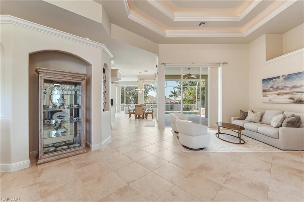 560 Inlet Drive Marco Island, FL 34145 - Photo 7 of 32 Living room with crown molding, a tray ceiling, and light tile patterned flooring
