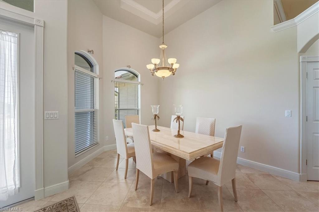 560 Inlet Drive Marco Island, FL 34145 - Photo 10 of 32 Dining area with high vaulted ceiling, a chandelier, light tile patterned floors, and arched walkways