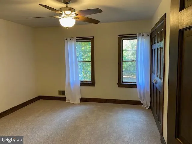 an empty room with windows and fan